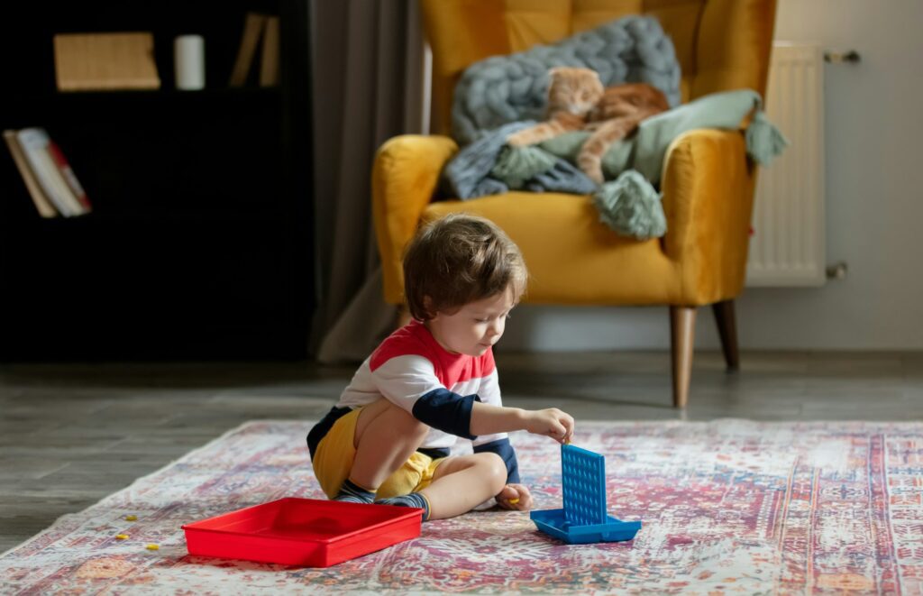 Little toddler boy play on floor and cat on background