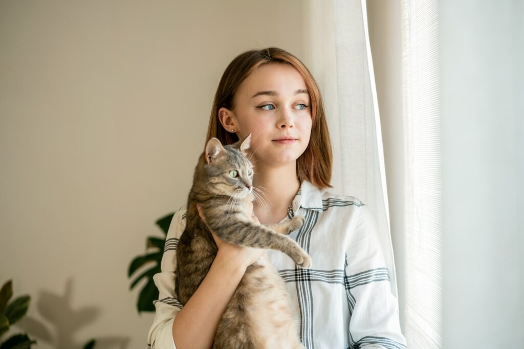 Woman looking at window with cat.